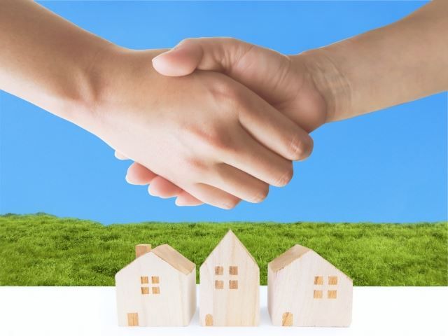 握手する手と家の模型